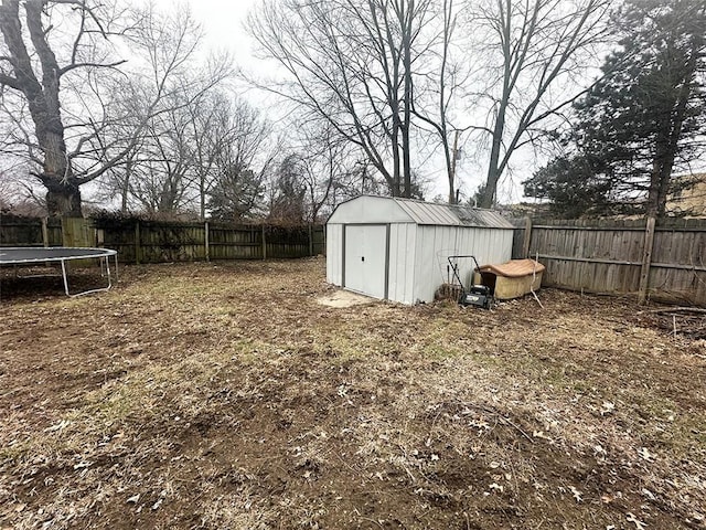 view of yard with a trampoline, a fenced backyard, an outdoor structure, and a storage unit