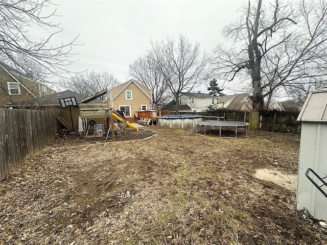 view of yard featuring a trampoline, a fenced backyard, a playground, and a fenced in pool