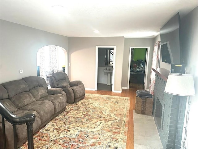 living room featuring arched walkways, light wood finished floors, and baseboards