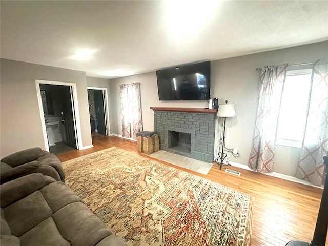 living area with a fireplace, a wealth of natural light, and wood finished floors