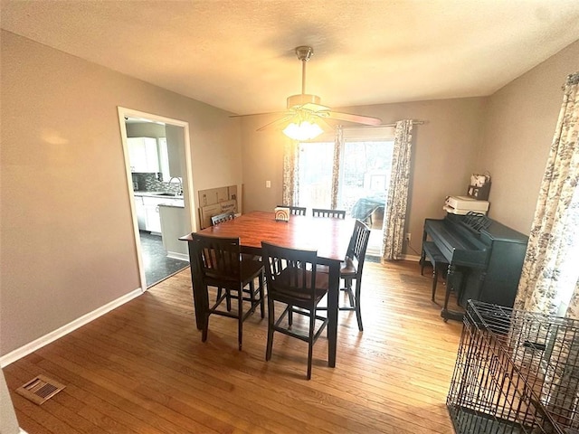 dining room featuring a ceiling fan, wood finished floors, visible vents, and baseboards