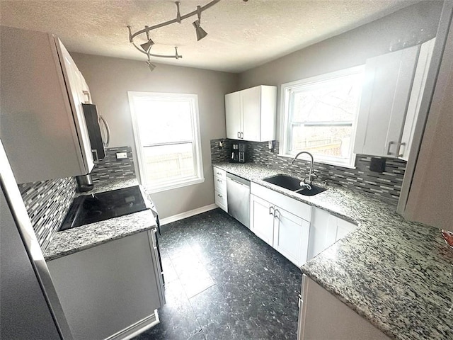 kitchen featuring light stone countertops, white cabinetry, stainless steel appliances, and a sink