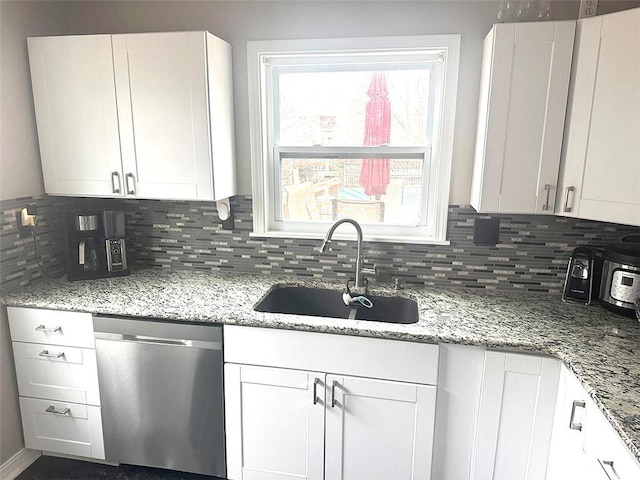 kitchen featuring tasteful backsplash, white cabinetry, a sink, and stainless steel dishwasher