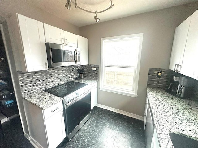 kitchen with light stone counters, stainless steel appliances, baseboards, white cabinets, and backsplash