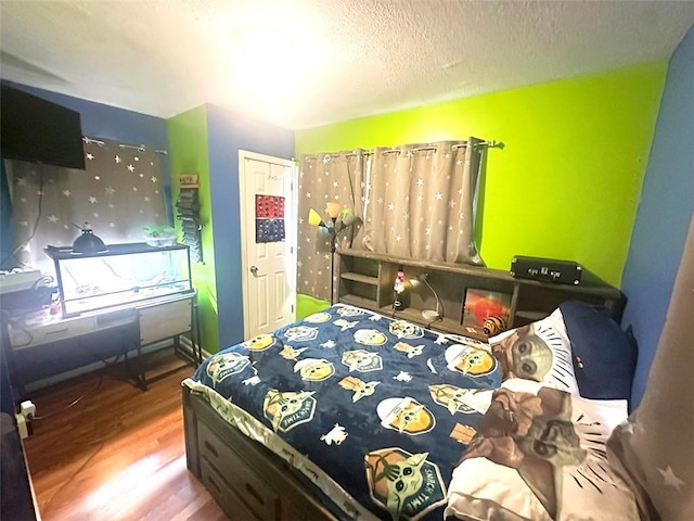 bedroom with a textured ceiling, wood finished floors, and baseboards