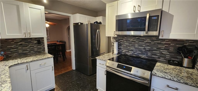 kitchen featuring stainless steel appliances, light stone counters, and white cabinetry