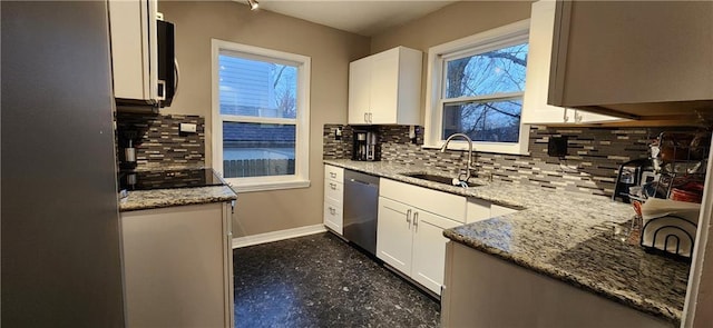 kitchen featuring stainless steel dishwasher, a sink, light stone countertops, and white cabinets