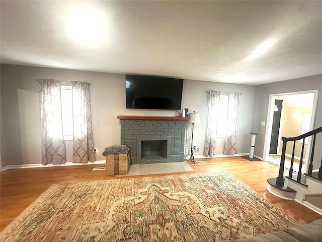 unfurnished living room featuring stairs, a fireplace, baseboards, and wood finished floors