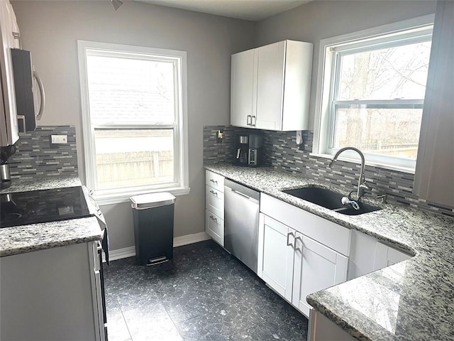 kitchen featuring stainless steel appliances, white cabinets, a sink, and light stone counters