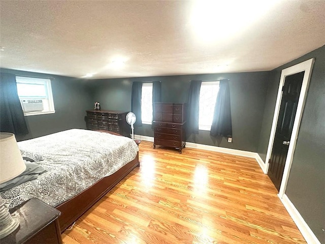 bedroom featuring light wood-style flooring, baseboards, and a textured ceiling