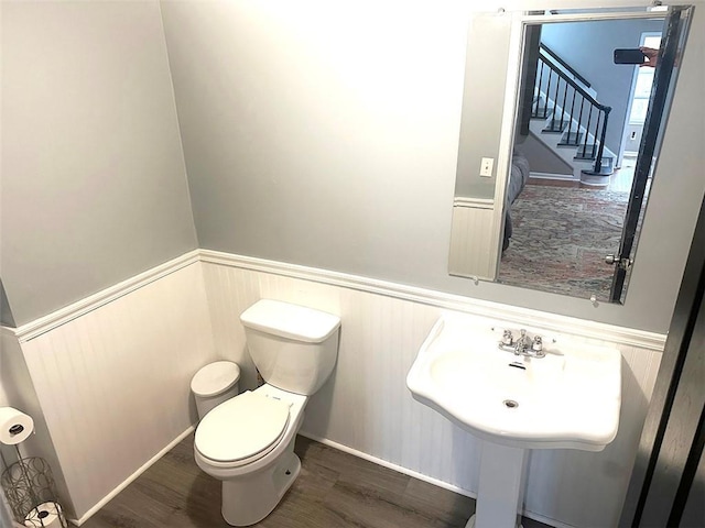 bathroom with wainscoting, wood finished floors, and toilet