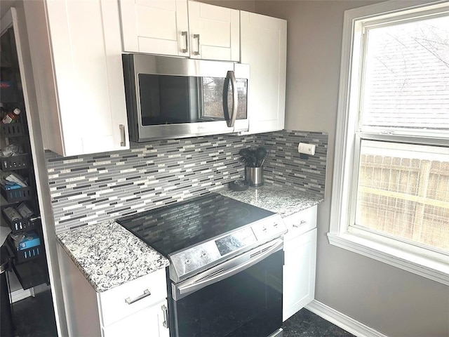 kitchen with stainless steel appliances, a healthy amount of sunlight, white cabinets, and decorative backsplash