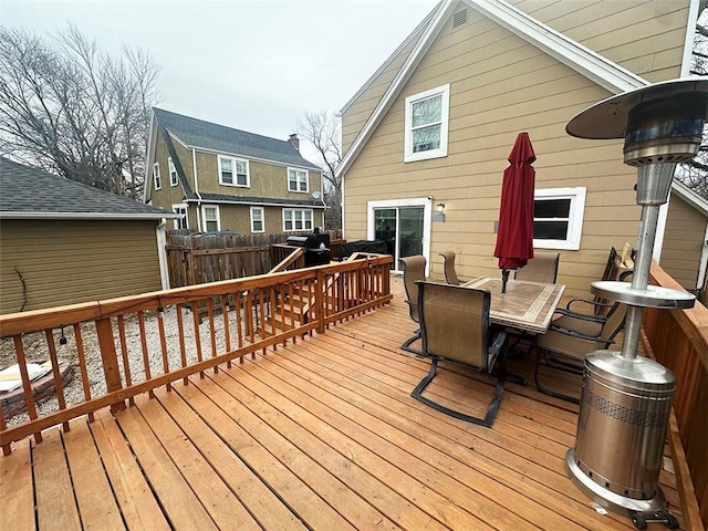 wooden deck with outdoor dining area, a grill, and fence