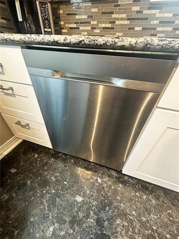 details featuring dark stone counters, white cabinets, and stainless steel dishwasher