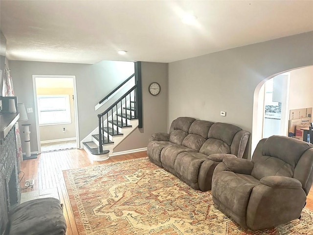 living area featuring stairs, arched walkways, baseboards, and wood finished floors