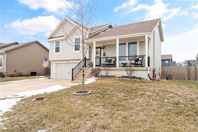 view of front of house with covered porch, a garage, cooling unit, and a front yard