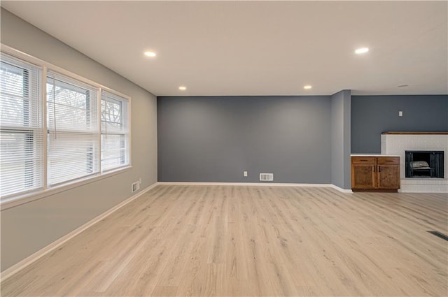 unfurnished living room with a fireplace and light hardwood / wood-style floors