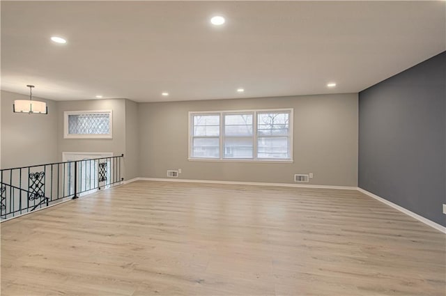 spare room with light hardwood / wood-style floors and a notable chandelier