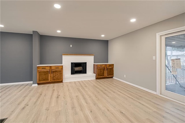 unfurnished living room with a fireplace and light wood-type flooring