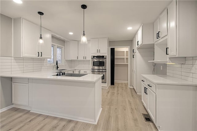 kitchen with white cabinetry, kitchen peninsula, stainless steel double oven, black electric cooktop, and light hardwood / wood-style flooring