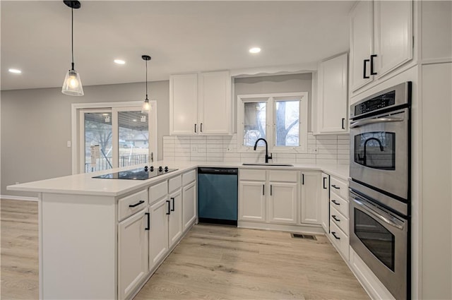 kitchen with sink, white cabinetry, kitchen peninsula, pendant lighting, and stainless steel appliances