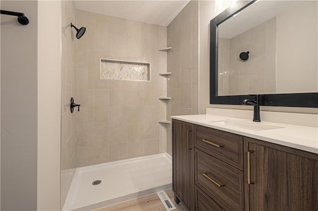 bathroom with a tile shower and vanity