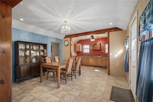 dining space with ceiling fan with notable chandelier, lofted ceiling, and sink