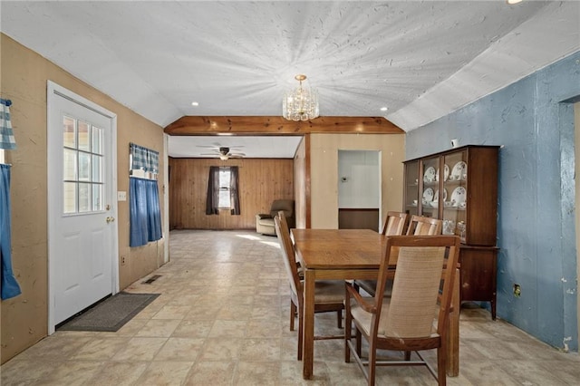 dining area featuring vaulted ceiling, wooden walls, and a chandelier