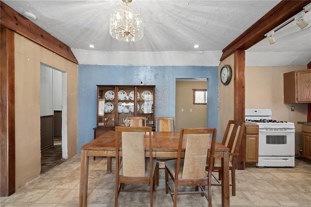 dining space with an inviting chandelier, beam ceiling, and a textured ceiling