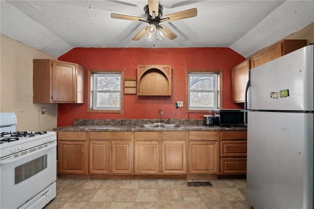 kitchen with a wealth of natural light, lofted ceiling, sink, white gas range, and fridge