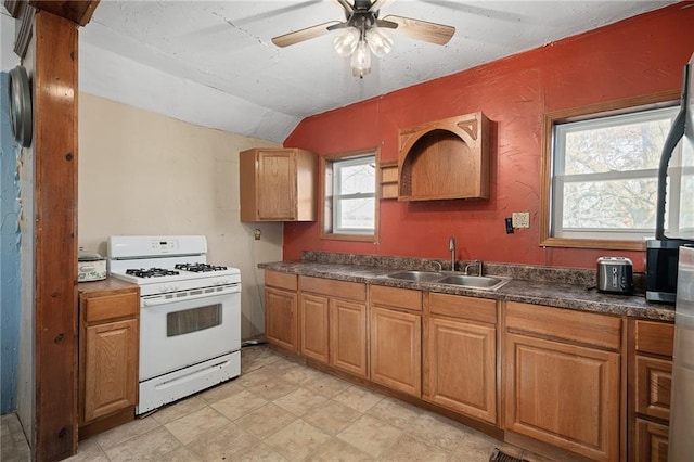 kitchen featuring white gas range, vaulted ceiling, sink, and ceiling fan