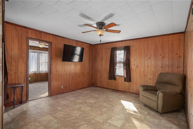 unfurnished room featuring crown molding, ceiling fan, and wood walls