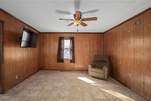 unfurnished room featuring ornamental molding, ceiling fan, and wood walls