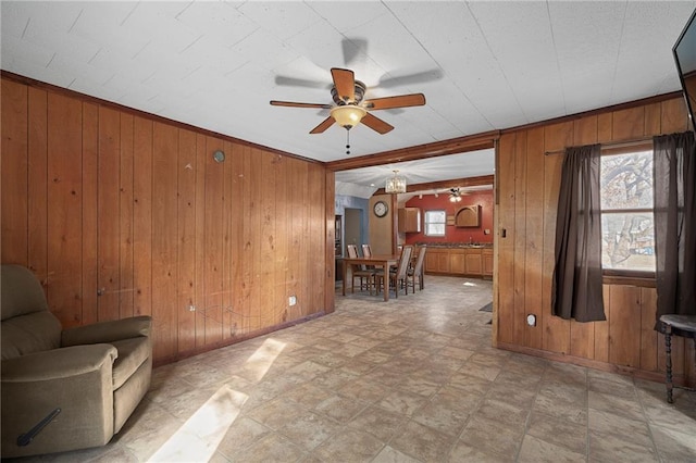 unfurnished living room featuring ceiling fan and wood walls