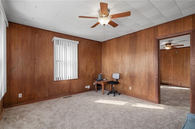 unfurnished office featuring ceiling fan, light carpet, and wooden walls