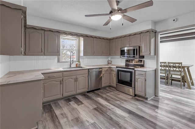 kitchen with sink, hardwood / wood-style flooring, backsplash, and appliances with stainless steel finishes