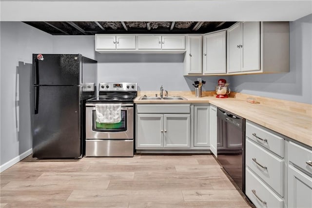 kitchen with sink, wooden counters, black appliances, light hardwood / wood-style floors, and white cabinets