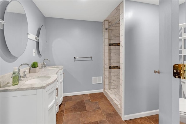 bathroom featuring tiled shower, vanity, and toilet