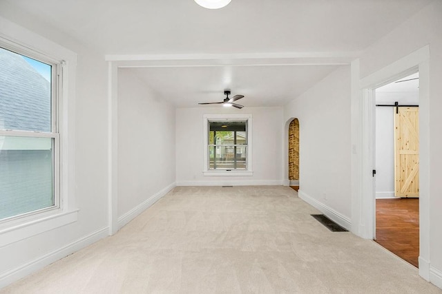 spare room with ceiling fan, light colored carpet, and a barn door