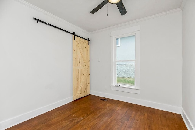 spare room with crown molding, wood-type flooring, a barn door, and ceiling fan