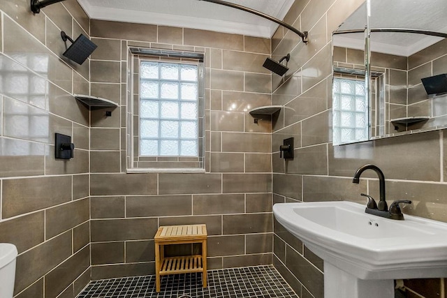 bathroom featuring sink, tile walls, decorative backsplash, tiled shower, and toilet