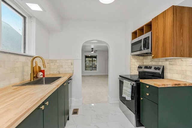 kitchen featuring stainless steel appliances, sink, backsplash, and wood counters