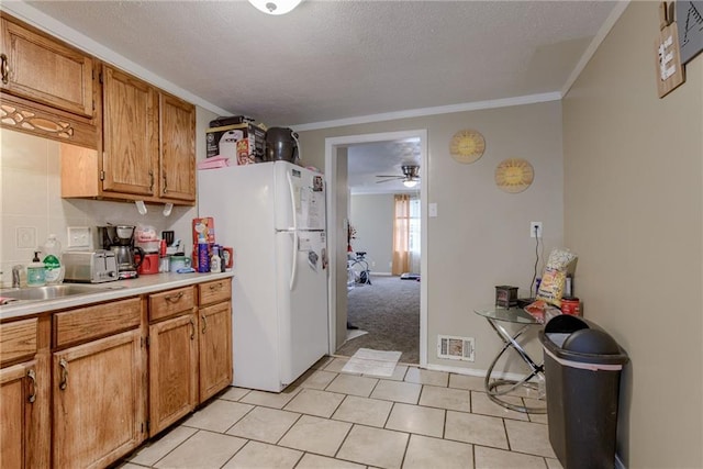 kitchen with ceiling fan, visible vents, crown molding, light countertops, and freestanding refrigerator