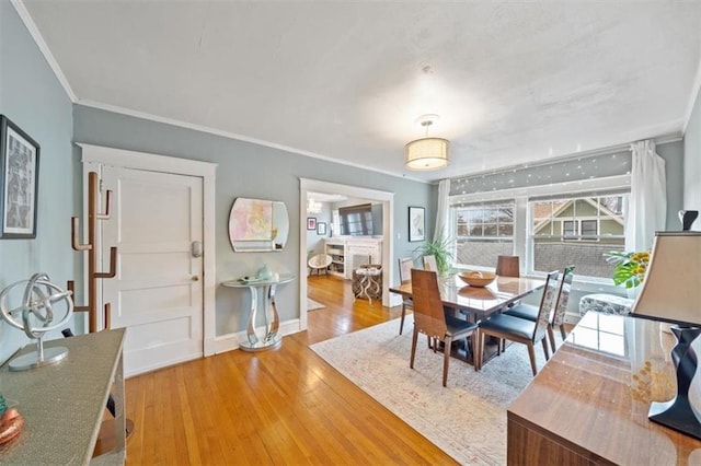 dining room featuring crown molding, hardwood / wood-style floors, and a fireplace