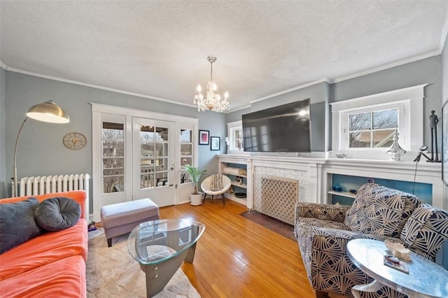 living room with an inviting chandelier, radiator heating unit, a textured ceiling, and a fireplace