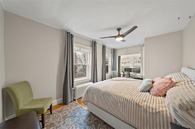 bedroom featuring wood-type flooring, radiator heating unit, and ceiling fan