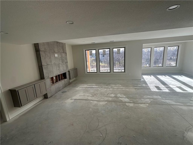 unfurnished living room featuring a tile fireplace and a textured ceiling