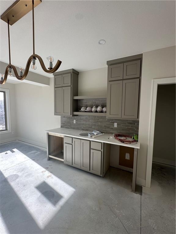 kitchen featuring pendant lighting, gray cabinets, sink, and tasteful backsplash