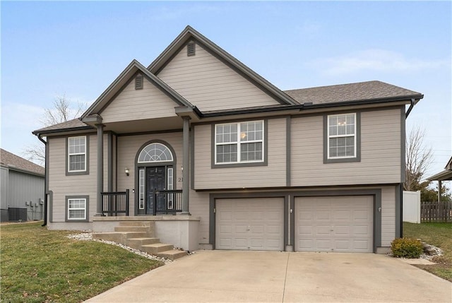 split foyer home featuring cooling unit, a garage, and a front yard