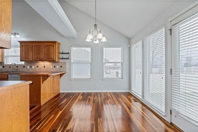 kitchen with dark wood-type flooring, a kitchen bar, sink, tasteful backsplash, and hanging light fixtures